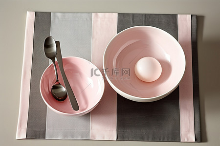 一个开胃菜盘，里面有两个粉色碗勺和灰色餐巾