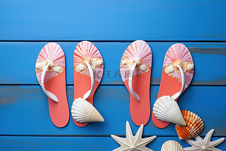 蓝色木质背景上铺着两只带贝壳的粉红色拖鞋