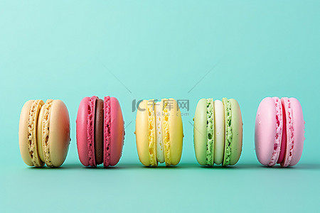 食物蛋白背景图片_薄荷绿色背景上排列在一起的五个彩色蛋白杏仁饼干