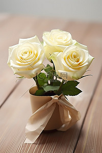 木桌和牛皮纸上迷你花瓶里的两朵白玫瑰
