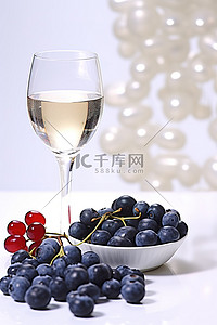樱桃蓝莓背景图片_白桌上的一杯白葡萄酒和蓝莓