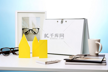 文件盒子背景图片_白纸活页夹装在黄色和蓝色三角形盒子里，上面有两个太阳镜和眼镜，放在白色桌子上
