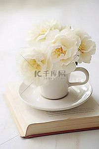 白花花的雪背景图片_白色木墙上一本打开的书上白色瓷杯里的三朵白花