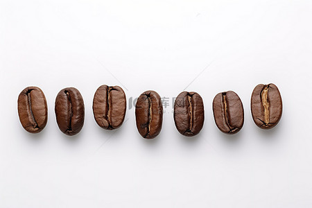 咖啡棕色背景图片_白色表面上的一排深色咖啡豆