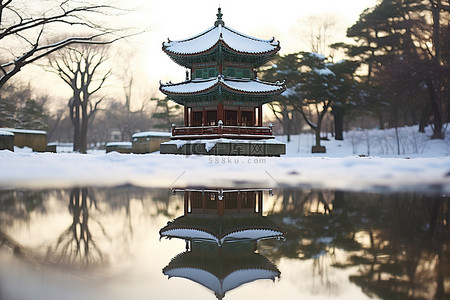 冬天古建筑背景图片_公园里的玻璃反射着雪中的宝塔