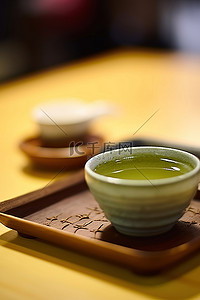一杯绿茶背景图片_桌子上放着一杯绿茶，旁边放着一碗茶