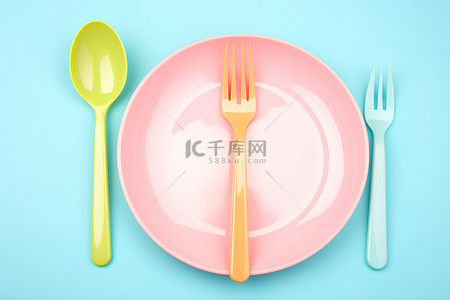空盘子背景图片_蓝色背景上的粉色盘子和叉子套装