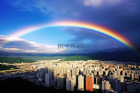 彩虹山背景图片_彩虹正在山附近的一座城市上空升起
