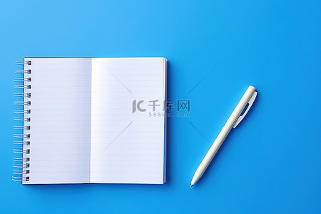 圆珠笔蓝色背景图片_一个打开的书写笔记本，上面有一支笔和一张蓝色的纸