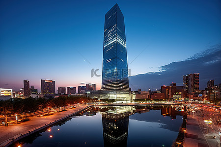 夜景建筑城市背景图片_黄昏时分一座方形建筑和一座高塔的图像