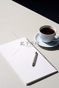 桌上放着一杯空的白色笔记本咖啡和笔