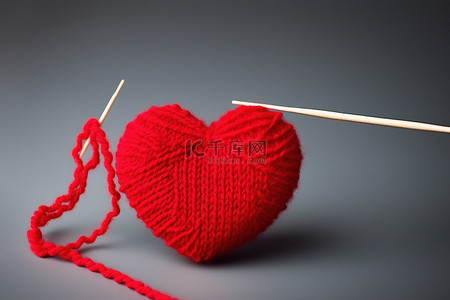 红色羊毛和一根织针位于红色心形的顶部