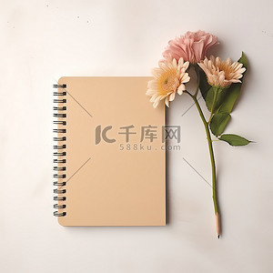 白色表面上的笔记本和铅笔，旁边是两朵粉红色的花