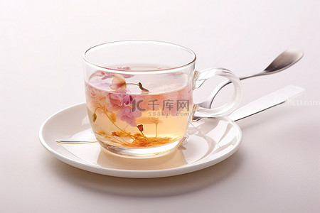 一个玻璃杯，里面装有香水，放在白盘子和勺子上