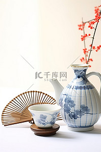 特产清酒背景图片_桌子旁边有一个壶茶碗和一把风扇