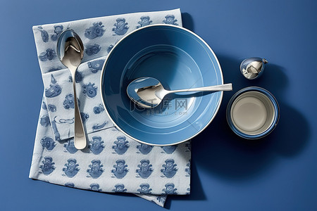 蓝色的盘子背景图片_一个蓝色的盘子，上面有银勺子和蓝色的碗