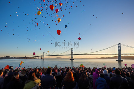 海湾旅游背景图片_一群人聚集在一起观看气球飞过海湾大桥