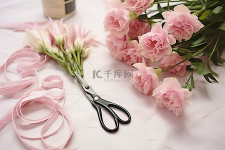 一把剪刀旁边有粉色的花朵和粉色的工艺品