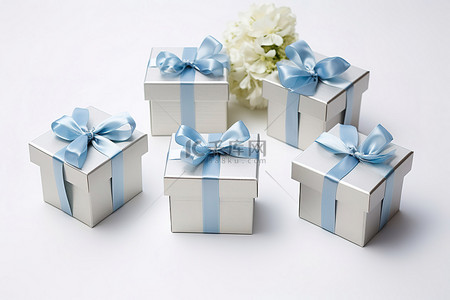 四个较小的银色盒子，上面有蓝色丝带和带有白色蝴蝶结的花朵
