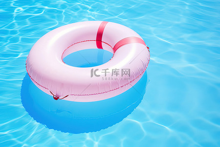 夏天游泳圈背景图片_漂浮在蓝色水中的白色游泳圈