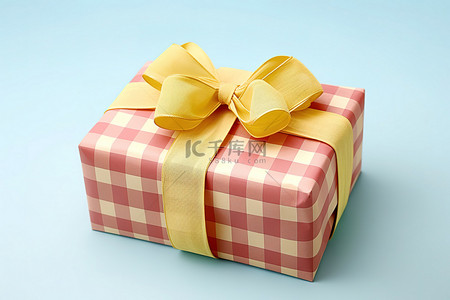 黄色礼物盒子背景图片_一个长方形的盒子，上面覆盖着黄色和粉色的格子丝带