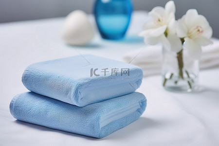 毛巾花背景图片_一堆带蓝色肥皂和蓝色花的白毛巾