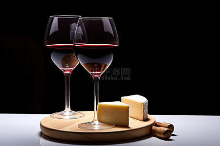 两个红酒杯和马苏里拉奶酪片站在桌子旁边，后面有黑光