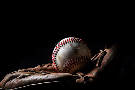 黑色背景中的手套里坐着一个棒球