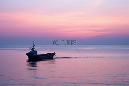 夕阳红背景图片_一艘小船漂浮在海洋中，夕阳红红