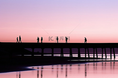 人的剪影背景图片_海滩退潮时码头上人们的剪影