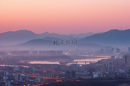 城市日出背景图片_日出时看到新明市的城市和山脉景观