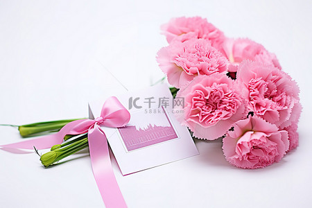 粉红色康乃馨和一张带丝带的感谢卡