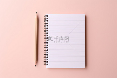 粉红色背景上带铅笔的纸质笔记本