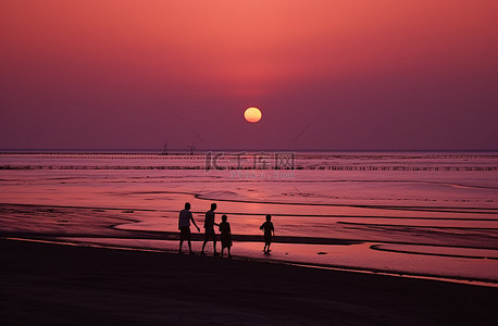 太阳海滩背景图片_日落时分，四个孩子正在靠近太阳的海滩上散步