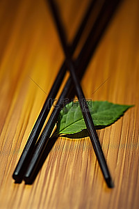 带叶子的黑色和绿色筷子坐在木桌上