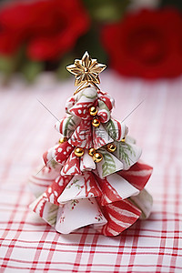 一块折叠的圣诞织物树，放在红白格子布上