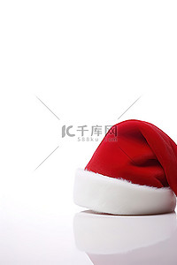 白色的球背景图片_一顶红色的圣诞老人帽子，白色表面上有一个白色的球