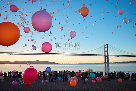 许多气球漂浮在桥前的海滩上
