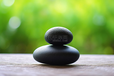 两块黑色石头坐在桌子上，靠近美丽的绿色背景