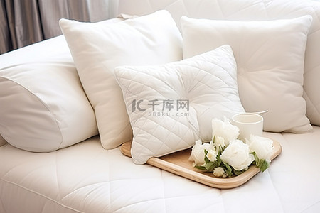 沙发上的白色枕头，托盘上装满牛奶和鲜花