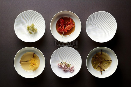 四个白盘子叠在一起，里面装着不同种类的茶
