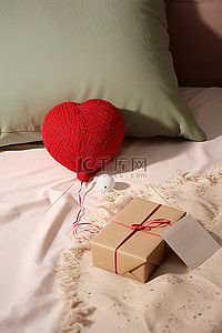 一张床上放着一个红色的毛线球和一份礼物