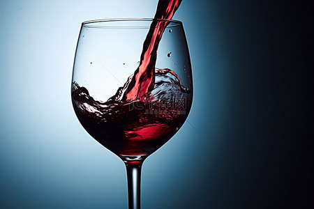 红酒……背景图片_蓝色背景中倒入玻璃杯的葡萄酒