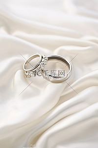 衣服挂拍背景图片_两枚结婚戒指放在一件白色衣服上