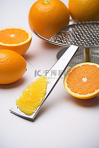 白桌上放着柑橘削皮器和刨丝器的橙片