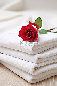 一朵粉红玫瑰坐在四块亚麻毛巾的中间