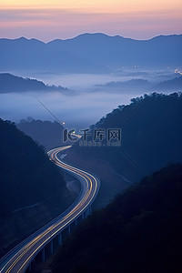 雾天行驶背景图片_一条高速公路在有雾的背景的山中行驶