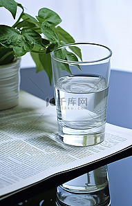 英文报纸背景图片_一杯水和植物在报纸上的纸上