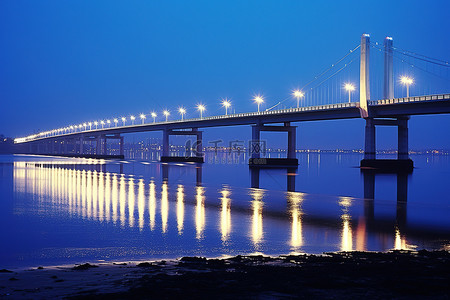 桥夜景背景图片_湖岸上的桥在晚上被灯光照亮