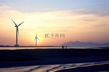 长沙滩上日落时的三台风力涡轮机